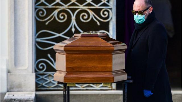 3月20日，一名男子戴著口罩在倫巴第附近貝加莫附近的塞裏泰（Seriate）封閉公墓舉行的葬禮中（他站在母親的棺材旁）