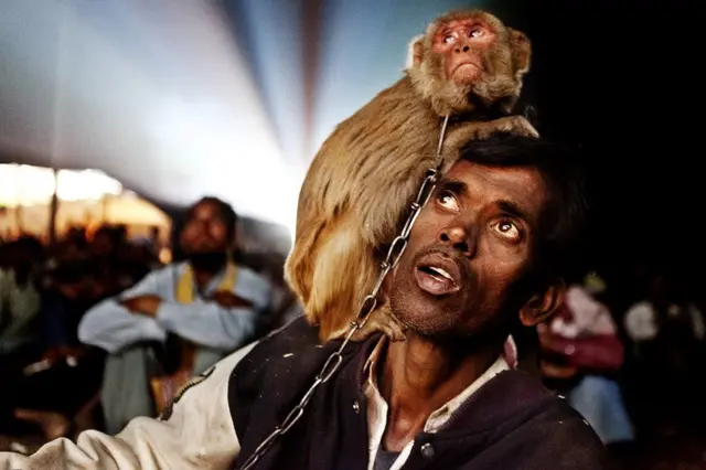 ટ્રાવેલિંગ સિનેમા નિહાળતા વાંદરા સાથેના વ્યક્તિનો ફોટો