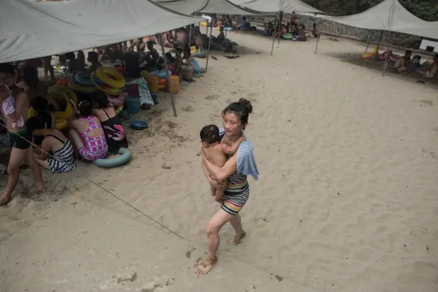 남포시 외곽의 한 해변가에서 아이를 안은 한 여성