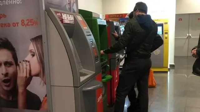 Банкоматдан пул чиқараётган мигрантлар