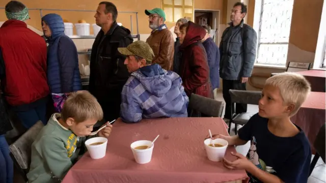 Nikita, 7 ans, et son frère Yegor, 8 ans, déjeunent dans une soupe populaire récemment ouverte à Izium, une ville récemment libérée par l'Ukraine. De nombreux magasins et commerces locaux ont été détruits.