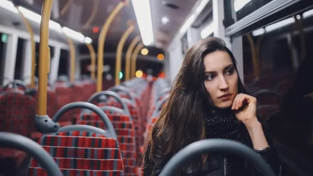 فتاة تجلس وحيدة وشاردة الذهن في حافلة عامة