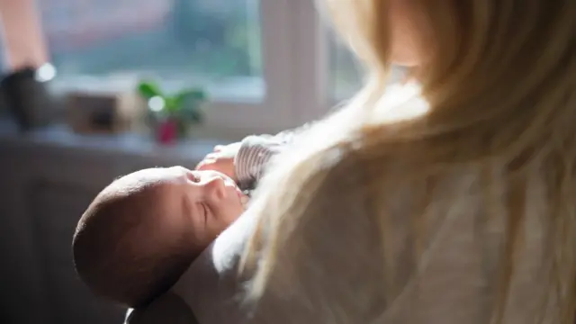 Una mujer carga un bebé