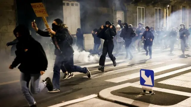 Protesters run amid clashes as they attend a demonstration on the day the National Assembly debates and votes on two motions of no-confidence against the French government, tabled by centrist group Liot and far-right Rassemblement National party, for its use of article 49.3, a special clause in the French Constitution, to push the pensions reform bill through the National Assembly without a vote by lawmakers, in Bordeaux, France, March 20, 2023