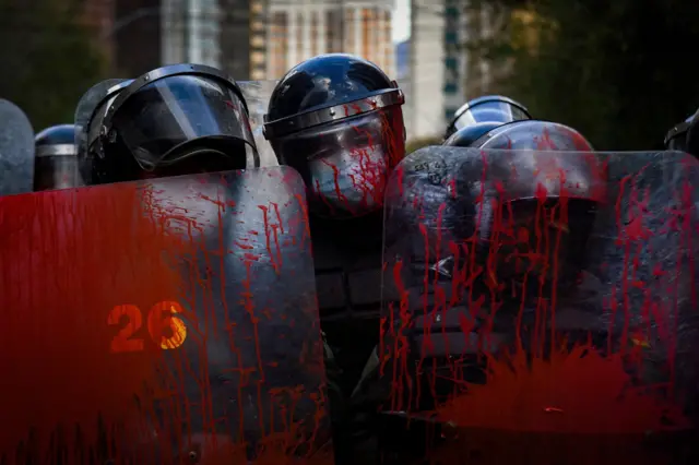 Police officers stand guard with their shields covered in red paint during a protest held by teachers against a new curriculum established by Bolivia's Ministry of Education, in La Paz, Bolivia, April 10, 2023.