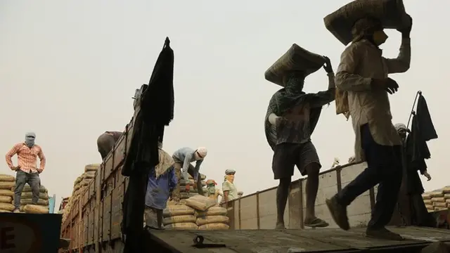 లారీ నుండి సరుకులను దింపుతున్న మగవారు