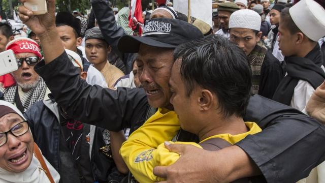 Seorang anggota kelompok anti-Ahok mengenakan topi dengan lambang bendera Hizbut Tahrir Indonesia, yang akan dibubarkan oleh pemerintah.