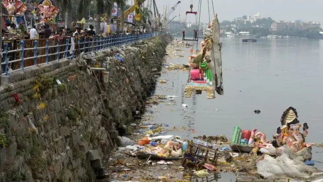 Indianos observam um guindaste abaixar uma imagem do deus hindu Ganesh nas águas do lago Hussain Sagar no festival religiososuper sic bosetembrosuper sic bo2018super sic boHyderabad.