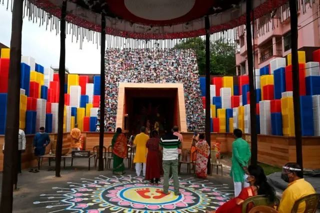 পুষ্পাঞ্জলি দিচ্ছেন হিন্দু ধর্মাবলম্বীরা। এই পূজামণ্ডপেও আছে করোনাভাইরাস ঠেকাতে সামাজিক সচেতনতার থিম।