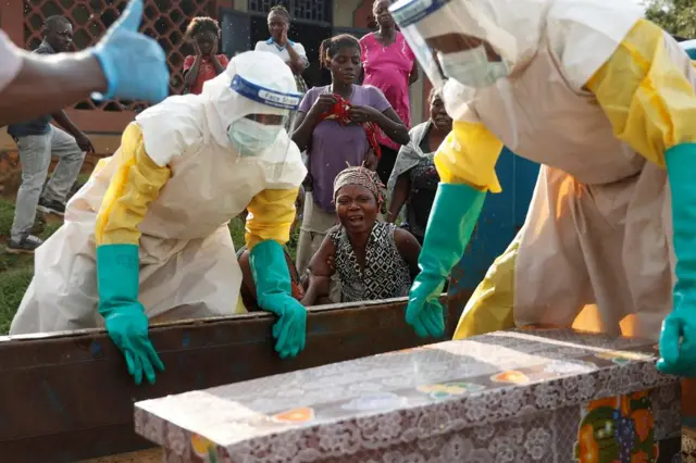 A mother of a child who died from suspected Ebola, cries near her child's coffin