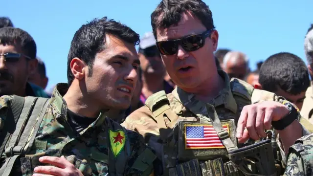 Un oficial estadounidense junto a un miembro de las YPG.