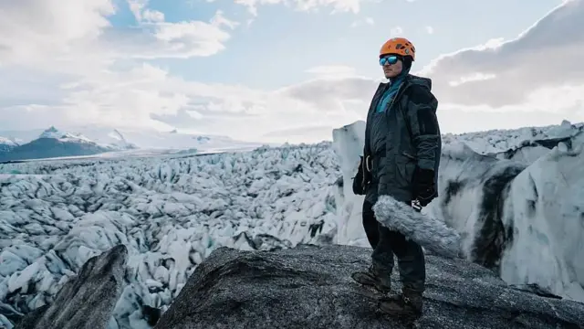 Vlasis con un micrófono en la mano en un glaciar