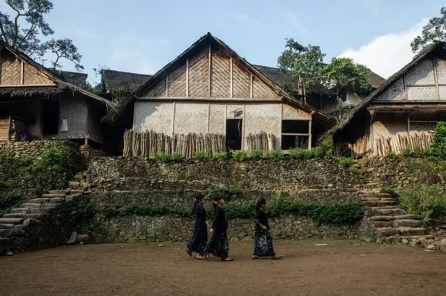 Tiga bocah anggota Suku Baduy berjalan melewati rumah tradisional, 19 Agustus 2021.