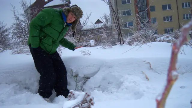 Tomasz Schafernaker pochyla się nad zaspą śniegu w Gdańsku w 2010 roku. Ma na sobie zieloną kurtkę i futrzaną czapkę
