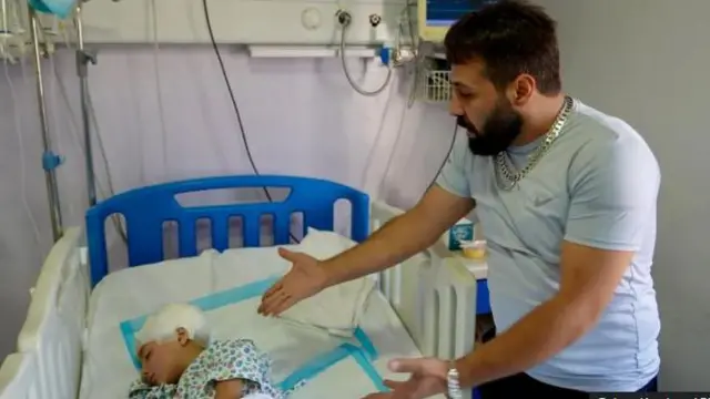 Noor ti ado oloro ba lori ree lori ibusun, baba re, Abdallah, lo n nawọ si i yii