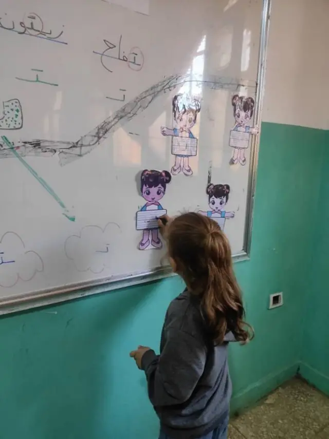 طفلة سورية تكتب على السبورة