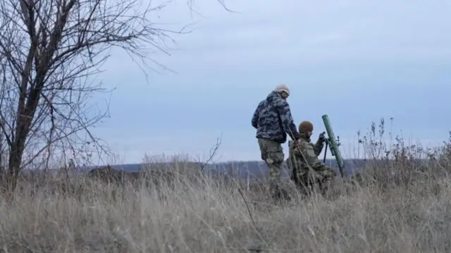 Двое украинских военных в поле с пусковой установкой.