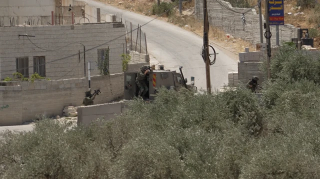 قوات إسرائيلية تصوّب بنادقها من خلف مركبة عسكرية في قرية المغير الفلسطينية، قرب رام الله، في الضفة الغربية المحتلة، في 11 يوليو/تموز 2026