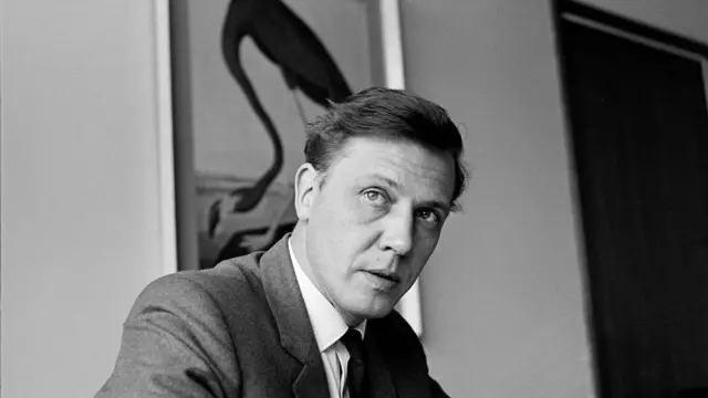 David Attenborough'nun BBC'de yönetilik yaptığı dönemde çekilmiş takım elbiseli siyah beyaz bir fotoğrafı. 