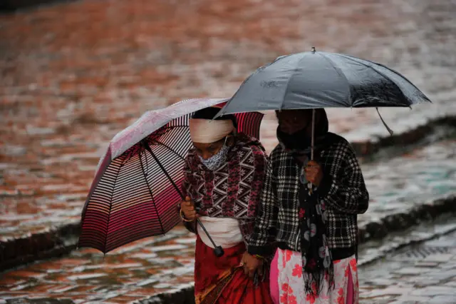 पानी पर्दा छाता ओढेर हिँडिरहेका महिलाहरू