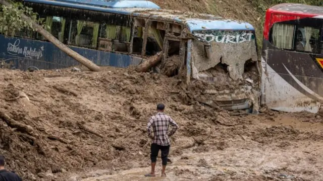 पहिरोले पुरिएका बस हेर्दै एक व्यक्ति