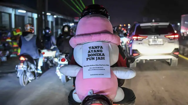 Pemudik bersepeda motor membonceng boneka saat melintas di jalur Pantura, jalan Raya Klari, Karawang, Jawa Barat, Rabu (19/04)
