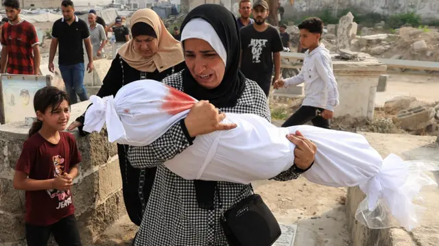 تحمل الفلسطينية سهى طافش جثمان حفيدتها سارة أبو دف، التي قُتلت في غارة إسرائيلية في مدينة غزة.