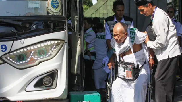 Petugas membantu seorang calon haji masuk ke dalam bus saat keberangkatan di Asrama Haji Embarkasi Surabaya (AHES), Surabaya, Jawa Timur, Senin (10/6/2024).
