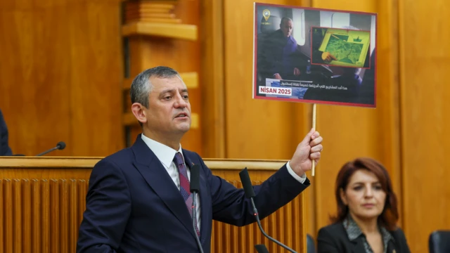 CHP Genel Başkanı Özgür Özel, Cumhurbaşkanı Erdoğan'ı havadan proje incelerken gösteren bir görsele ait kartoneti elinde tutuyor. Helikopterdeki Erdoğan karşısındaki yetkilinin anlattıklarını dinliyor.