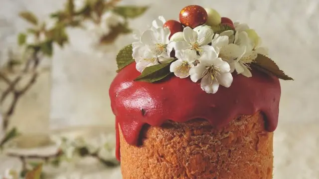 Паска з ягідною глазур'ю червоного кольору, прикрашена живими квітами. 