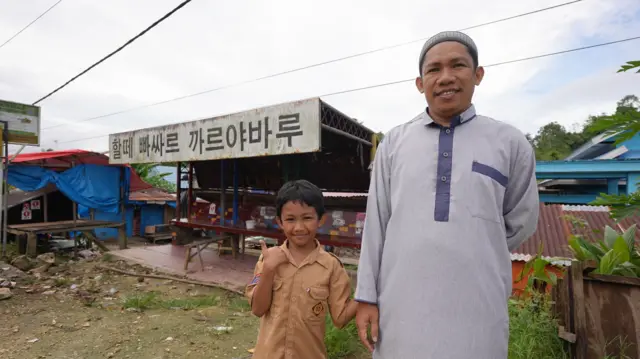 Yusminar bersama anaknya berpose di depan Halte Karya Baru, Baubau.