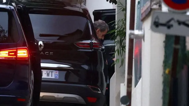 Саркози выходит из черной машины.