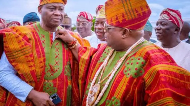 Deji ati Ademola Adeleke wọ asọ oke alawọ pupa ati goolu,wọn de fila asọ oke naa, wọn fi ilẹkẹ sọrun, Ademola n tun asọ naa se lọrun ẹgbọn rẹ