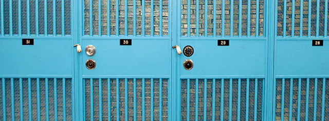 Lingotes de oro apilados hasta el techo bajo puertas con rejas azules en la Reserva Federal. 