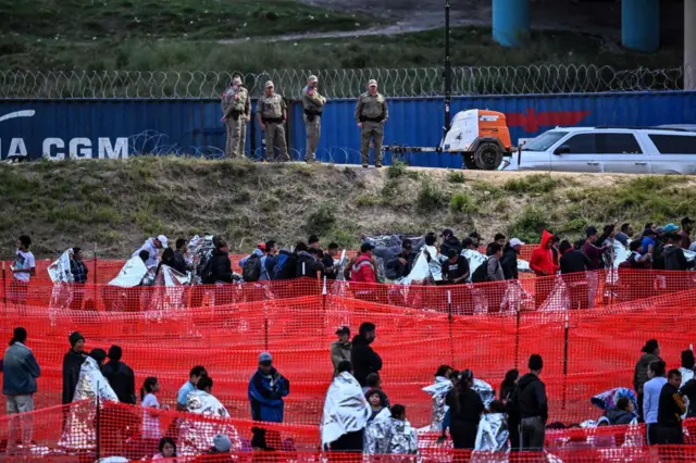 비상 담요를 덮은 채 국경 지역의 시설에서 대기하는 이민자들