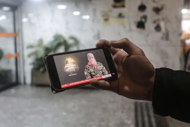 Un hombre palestino ve en su teléfono un discurso de Obeida a principios de 2025.