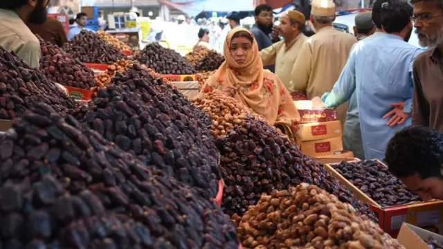 Seorang ibu membeli kurma di Karachi, Pakistan.