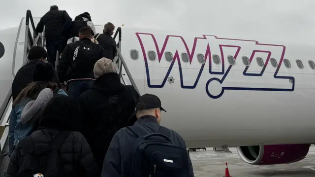 Ludzie wsiadają do samolotu Wizz Air w mglisty poranek na lotnisku w Balicach koło Krakowa, w Polsce, 27 listopada 2024 r.