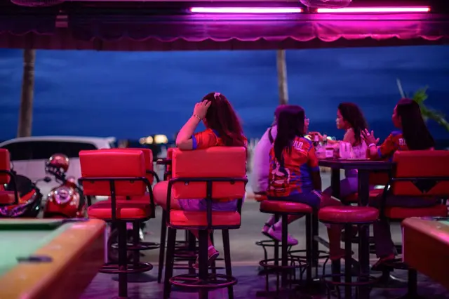 Employees have a rest as they wait for customers in a bar near Pattaya Beach, in Pattaya on June 29, 2026.
