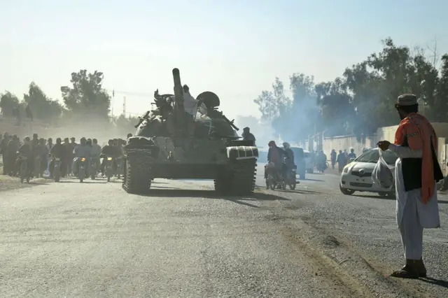 Taliban security personnel wey dey on top Soviet‑era tank get motorcyclists wey dey follow dem as dem ride go di border, during di ongoing clashes between Taliban security personnel and Pakistani border forces, for Spin Boldak district of Kandahar Province for October 15, 2025.