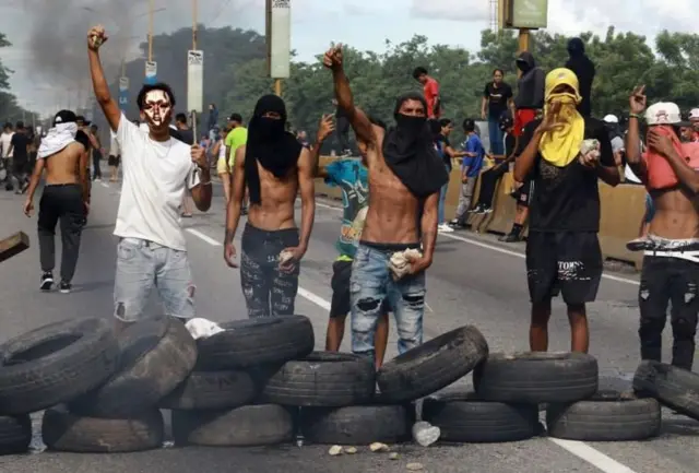 Foto colorida mostra manifestantes queimando pneus