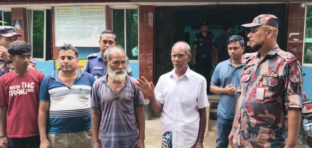 বকশীগঞ্জ থানায় ষষ্ঠী চন্দ্র বর্মনের সাথে ভাই, মেয়ের জামাই ও ভাইয়ের ছেলে। পাশে বিজিবির সদস্যরাও দাঁড়িয়ে আছেন।