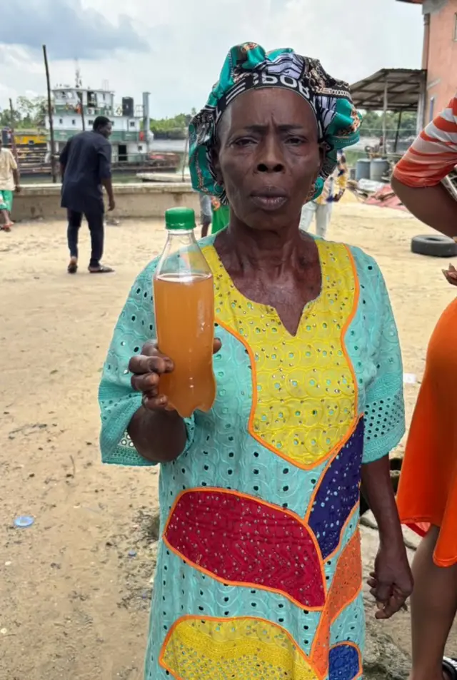 Woman wey hold polluted water inside bottle for Ofiomina-ama Alakiri community