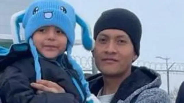 يظهر ليام كونيخو راموس، مرتدياً قبعة زرقاء فاتحة، في الصورة مع والده الذي يرتدي قبعة سوداء، واقفين خارج ما يبدو أنه سجن. كلاهما يبتسم للكاميرا.