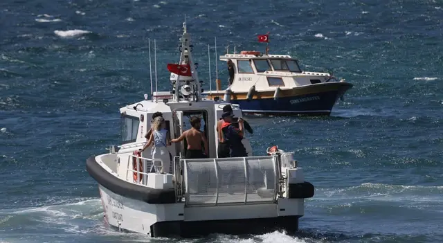 Tatilci olduğu anlaşılan kişiler deniz yoluyla tahliye edilirken görülüyor