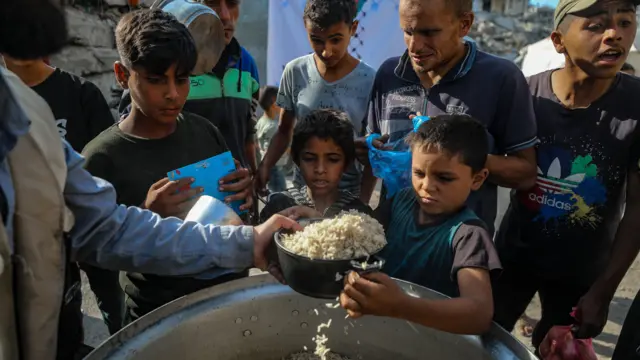 طفل فلسطيني يحاول الحصول على الغذاء من نقطة مساعدات
