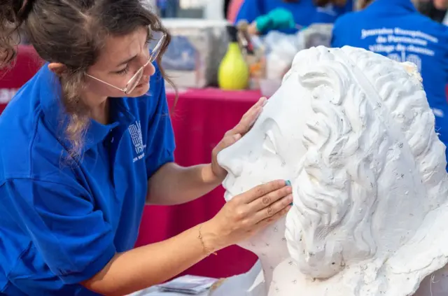 पॅरिसच्या नोत्र दामच्या डागडुजीदरम्यान प्लास्टरची मूर्ती तयार करणारी कलाकार