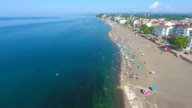 2024 yazında Akçakoca sahillerinde denize girenler, sahilin fotoğrafı kuş bakışı olarak çekilmiş, renkli şemsiyeler var.