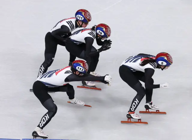 이탈리아 밀라노 아이스스케이팅 아레나에서 한국 쇼트트랙 여자 선수들이 국가대표 선수복을 입고 계주 훈련을 하고 있다. 네 명의 선수가 차례로 빙판을 돌며 손으로 등을 밀어주는 교대 동작을 반복하고 있다.