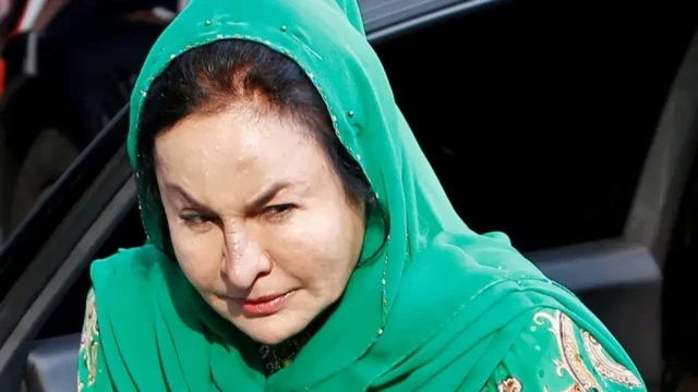 Rosmah Mansor sedang menggunakan hijab dan stelan baju hijau.